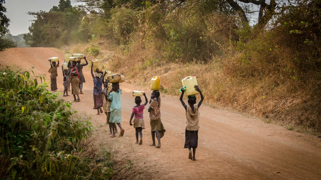 Villageois transportant des bidons d'eau sur une route de terre